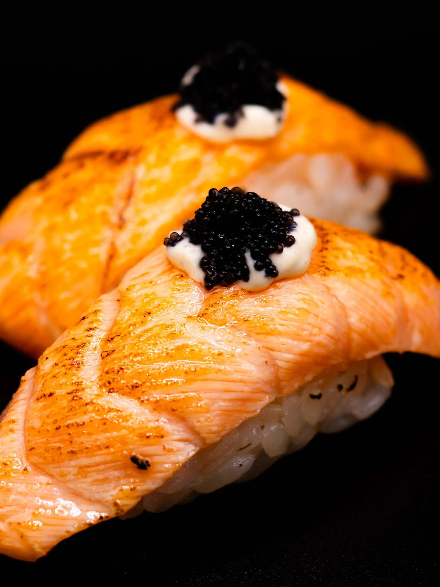 Nigiri de salmón flambeado con mayonesa trufada y tobiko negro, sobre fondo negro