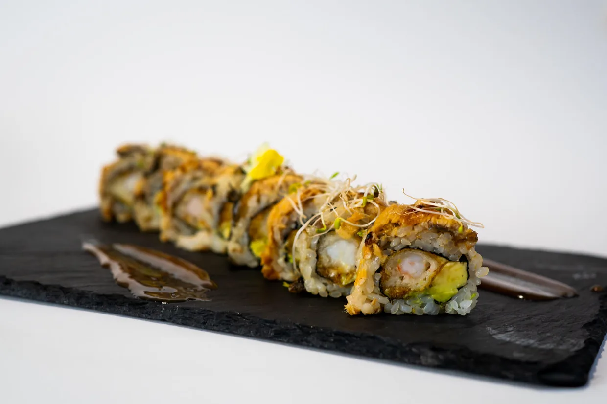 Roll mit Tempura-Auflage und Katsuobushi auf einer Schieferplatte