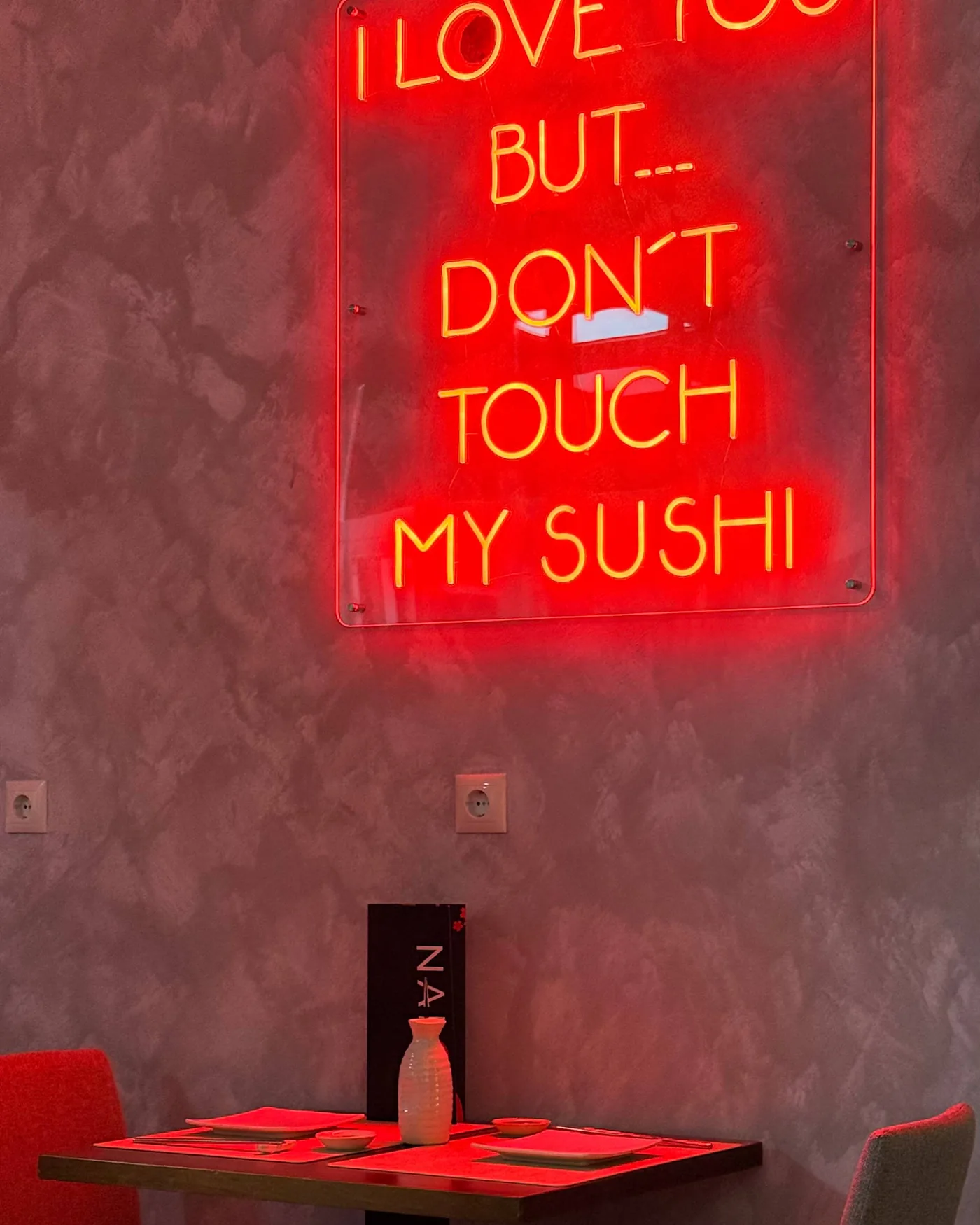 Sala del restaurante con el cartel de neón encendido sobre la pared y una mesa preparada